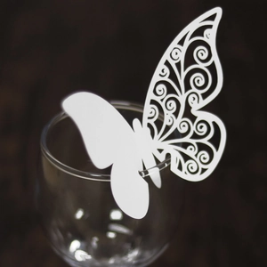 Macro detail of white laser-cut butterfly place card for wedding glassware decoration