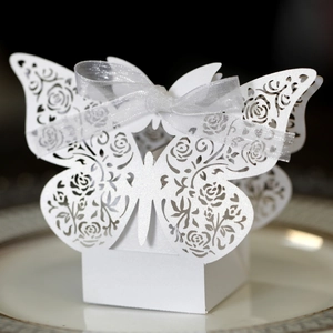 Macro detail of laser-cut butterfly gift box with rose patterns and white ribbon