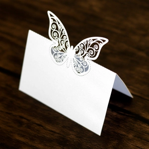 Vue détaillée de marque-places papillon blancs découpés au laser sur bois sombre