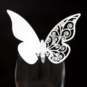 White butterfly paper place card with intricate laser-cut hollow design on glass rim