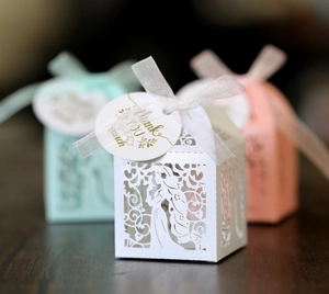 Detail of laser-cut hollow candy boxes with sheer ribbon bows and gold thank you tags