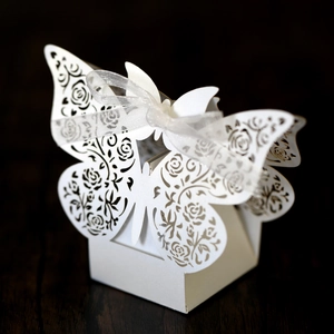 Detailed laser-cut white butterfly candy box with intricate floral hollows and silk ribbon