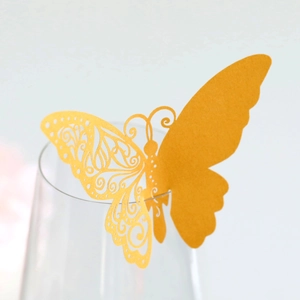Macro shot of a laser-cut golden butterfly place card attached to a glass rim for events