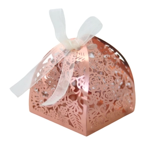 Détail du motif floral découpé au laser sur boîte cadeau or rose avec nœud blanc