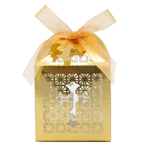 Macro detail of laser-cut cross favor box in gold with a matching organza ribbon bow