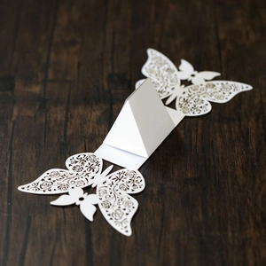 Detail of white laser-cut butterfly place card with standing fold on wood surface