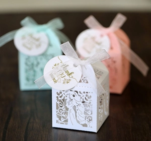 Detail of laser-cut gift boxes with floral patterns, ribbons, and thank you tags
