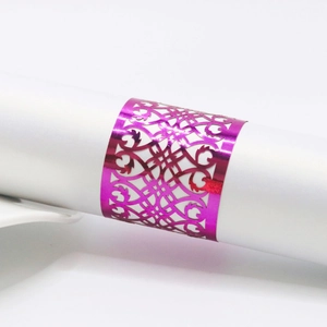Detail of rose red laser-cut napkin ring with ornate floral patterns on white roll