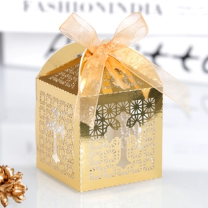 Detail of gold laser-cut favor box with cross patterns and a yellow ribbon bow