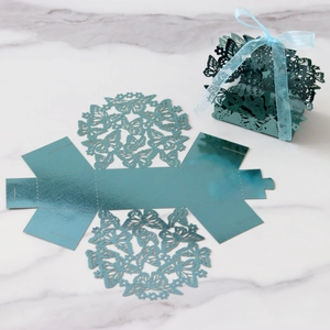 Detail of laser-cut hollow butterfly candy box in metallic blue with silk ribbon bow