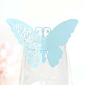 Close-up of laser-cut light blue butterfly place card on transparent wine glass rim