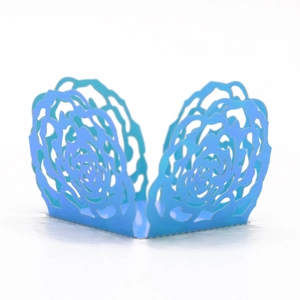 Close-up of bright blue laser-cut cupcake wrappers with intricate rose flower lace pattern