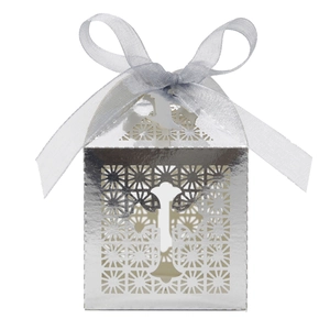 Detail of silver laser-cut candy box featuring hollow cross design and silk ribbon bow