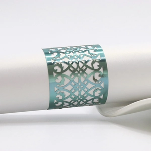 Macro view of blue metallic laser-cut napkin ring with intricate vine pattern on a white napkin