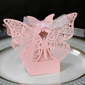 Close-up of pink laser-cut wedding favor box with rose patterns and white ribbon