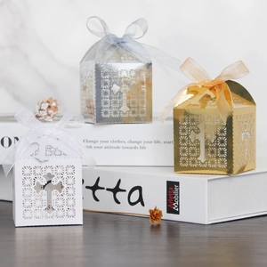 Laser-cut cross favor boxes in white, gold, and silver with elegant ribbon bows