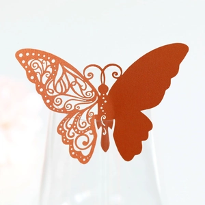 Close-up of laser-cut orange butterfly place card for wine glass wedding decoration