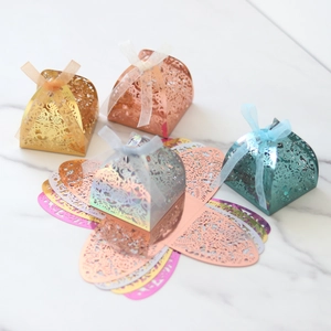 Détail de boîtes à bonbons ajourées laser avec motifs roses et rubans en organza soyeux