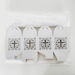 Flat lay of white laser-cut wedding favor boxes with cross pattern and silk ribbons