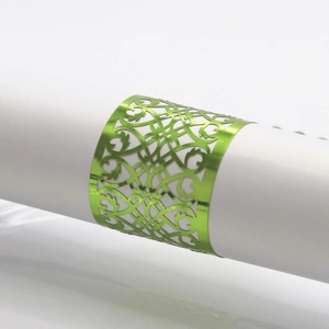 Detail of green laser-cut napkin ring with intricate floral patterns on a white napkin