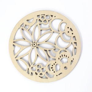 Close-up of laser-cut hollow sunflower pattern on round natural wood insulation coaster