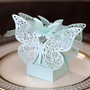 Detail of light blue laser-cut butterfly candy box with rose patterns and ribbon on a plate