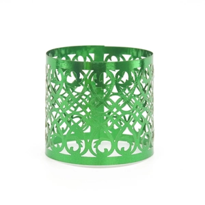 Close-up of laser-cut green metallic napkin ring with ornate floral scroll patterns
