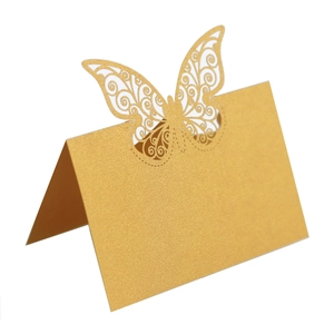 Gros plan d'une carte de table en papier perlé doré avec papillon découpé au laser