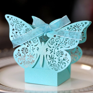 Macro shot of light blue laser-cut wedding favor box with butterfly top and ribbon