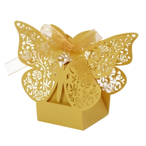 Close-up of laser-cut butterfly wedding favor box with gold rose patterns and ribbon
