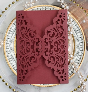Detail of wine red laser-cut wedding invitation cover with elegant floral vine patterns