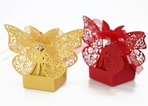 Detail of laser-cut butterfly wedding favor boxes with elegant gold and red floral patterns