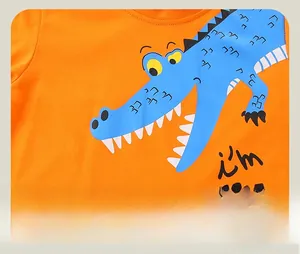 Close-up of bright orange cotton t-shirt with a blue cartoon crocodile print detail