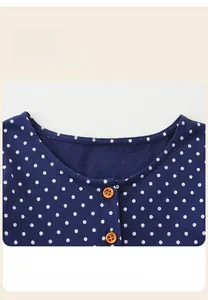 Detail of the navy blue polka dot neckline with round trim and brown wooden buttons