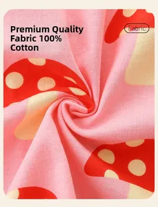 Gros plan sur un tissu en coton rose imprimé de champignons pour robes de fillettes