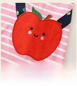 Gros plan d'une robe rayée rose avec broderie de pomme rouge mignonne et visage souriant