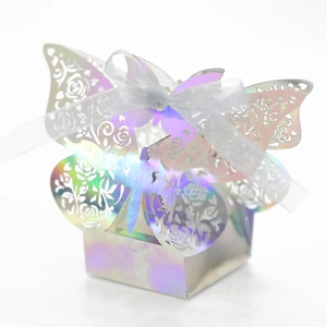 Detail of laser-cut iridescent butterfly favor box with rose patterns and white ribbon