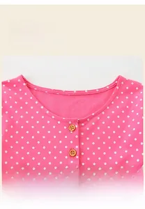 Gros plan du col en tricot rose à pois avec deux boutons en bois marron