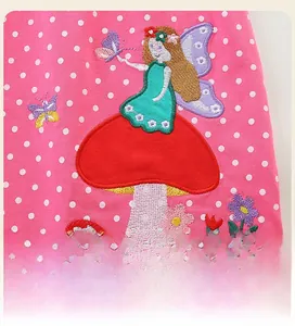 Détail de robe rose à pois en coton avec broderie de fée, de champignon et de papillon