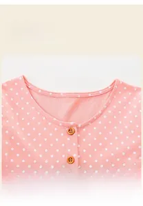 Détail de robe rose à pois pour fille montrant le col rond et les boutons en bois