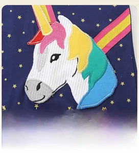 Detail of colorful unicorn embroidery on navy blue fabric with gold star patterns