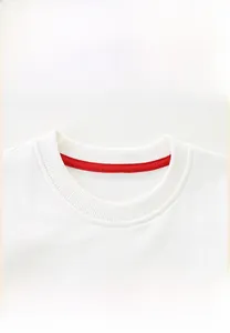 Détail d'un sweat en tricot blanc avec col rond côtelé et bande de propreté rouge au cou