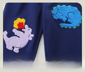 Detail of chenille dinosaur patches and soft knit fabric on navy kids joggers