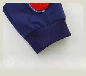 Detail of navy blue kids joggers featuring ribbed cuffs and red heart embroidered patch