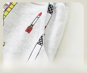 Détail de couture sur un pantalon gris pour enfant avec imprimé fusée de dessin animé