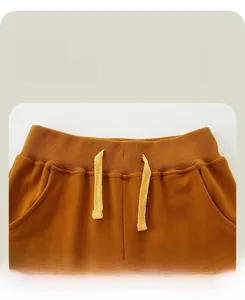 Detail of caramel kids' sports trousers with elastic drawstring waistband and side pockets