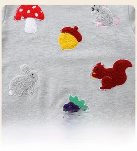 Vue détaillée de broderie bouclée thème forêt avec champignon et écureuil sur sweat gris