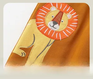 Close-up of lion head embroidery on orange cotton sports pants for boys and kids