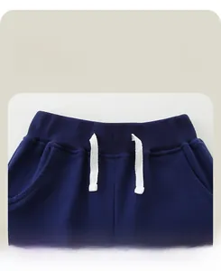 Detail of navy cotton jogger pants featuring an elastic ribbed waistband and white drawstrings