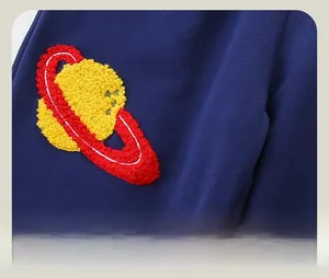 Detail shot of navy cotton sweatpants featuring a yellow and red planet embroidered patch